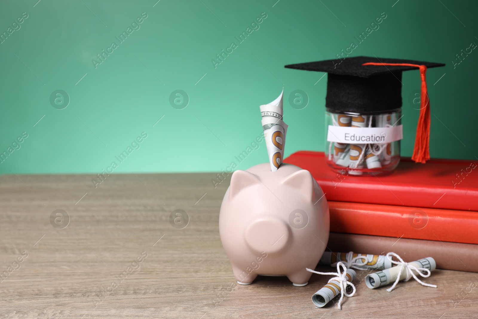 Photo of Piggy bank, graduate hat, books, dollar banknotes and glass jar with word Education on wooden table, space for text. Tuition payment