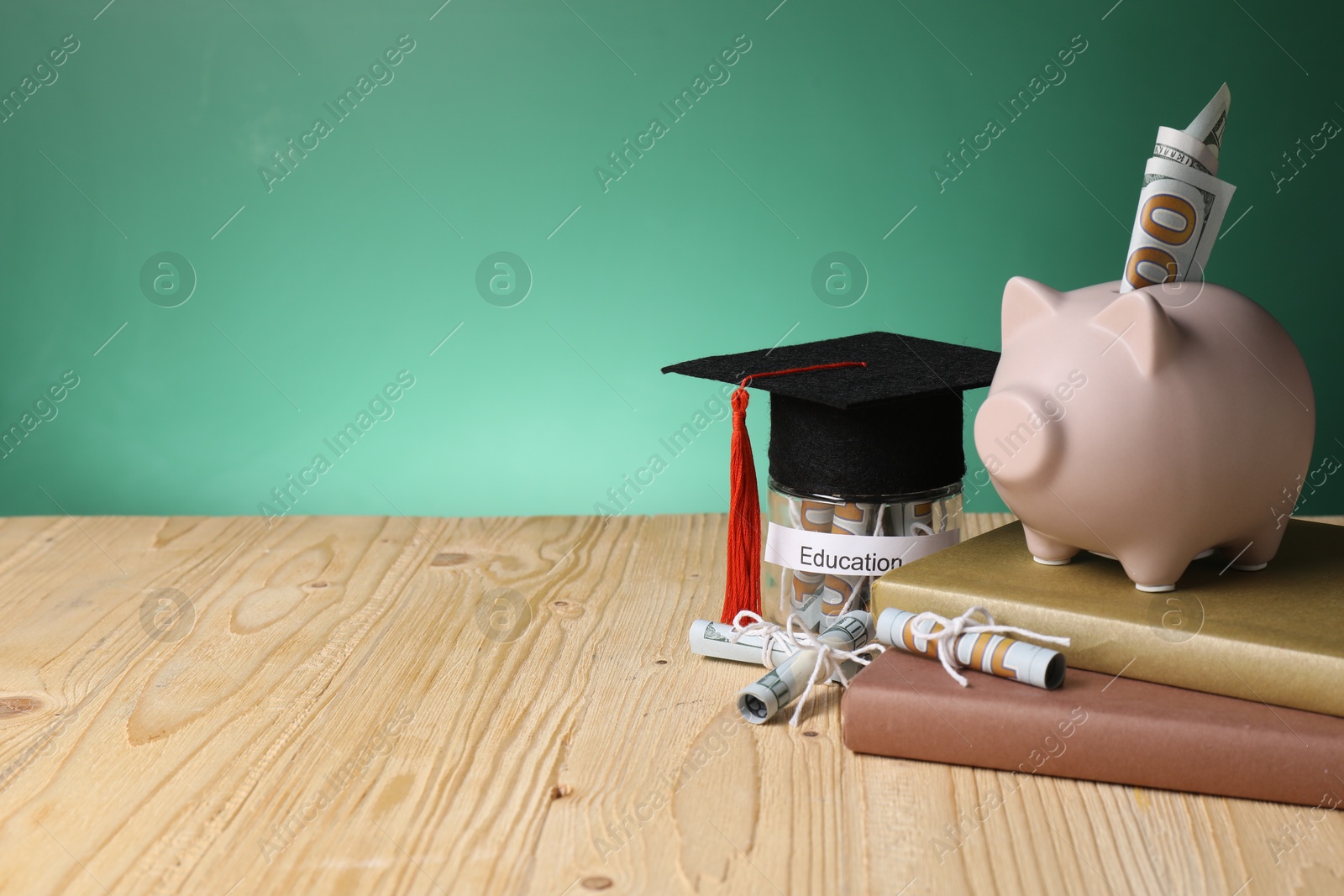 Photo of Piggy bank, graduate hat, books, dollar banknotes and glass jar with word Education on wooden table, space for text. Tuition payment