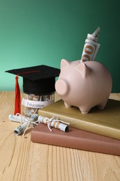 Photo of Piggy bank, graduate hat, books, dollar banknotes and glass jar with word Education on wooden table. Tuition payment