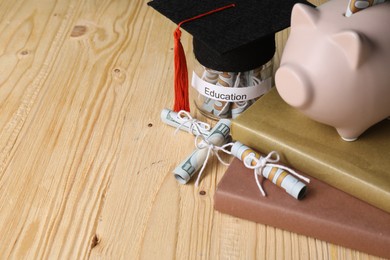 Photo of Tuition payment. Graduate hat, dollar banknotes, coins and glass jar with word Education on wooden table, closeup. Space for text