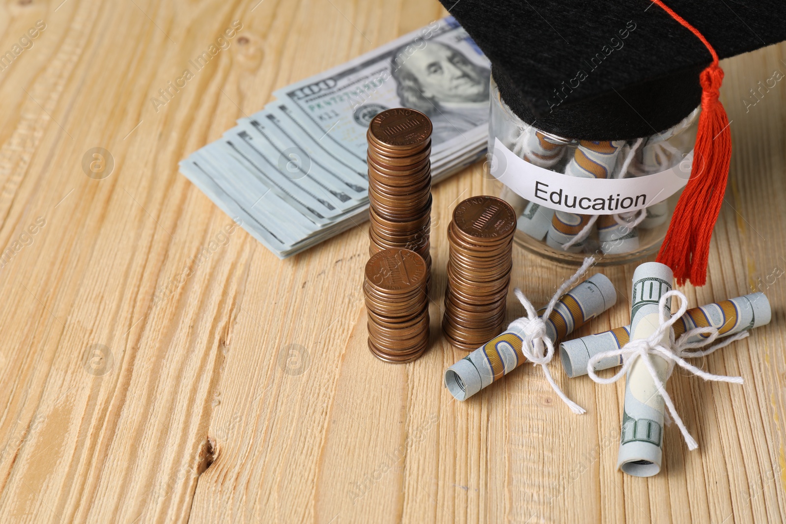 Photo of Tuition payment. Graduate hat, dollar banknotes, coins and glass jar with word Education on wooden table, closeup. Space for text