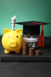 Photo of Piggy bank, graduate hat, coins, book and dollar banknotes in glass jar with word Education on black table. Tuition payment