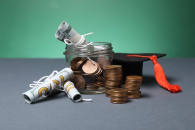 Photo of Dollar banknotes, coins and graduate hat on grey table. Tuition payment