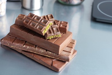 Stack of tasty Dubai chocolate bars with pistachios and knafeh on grey table, closeup. Space for text