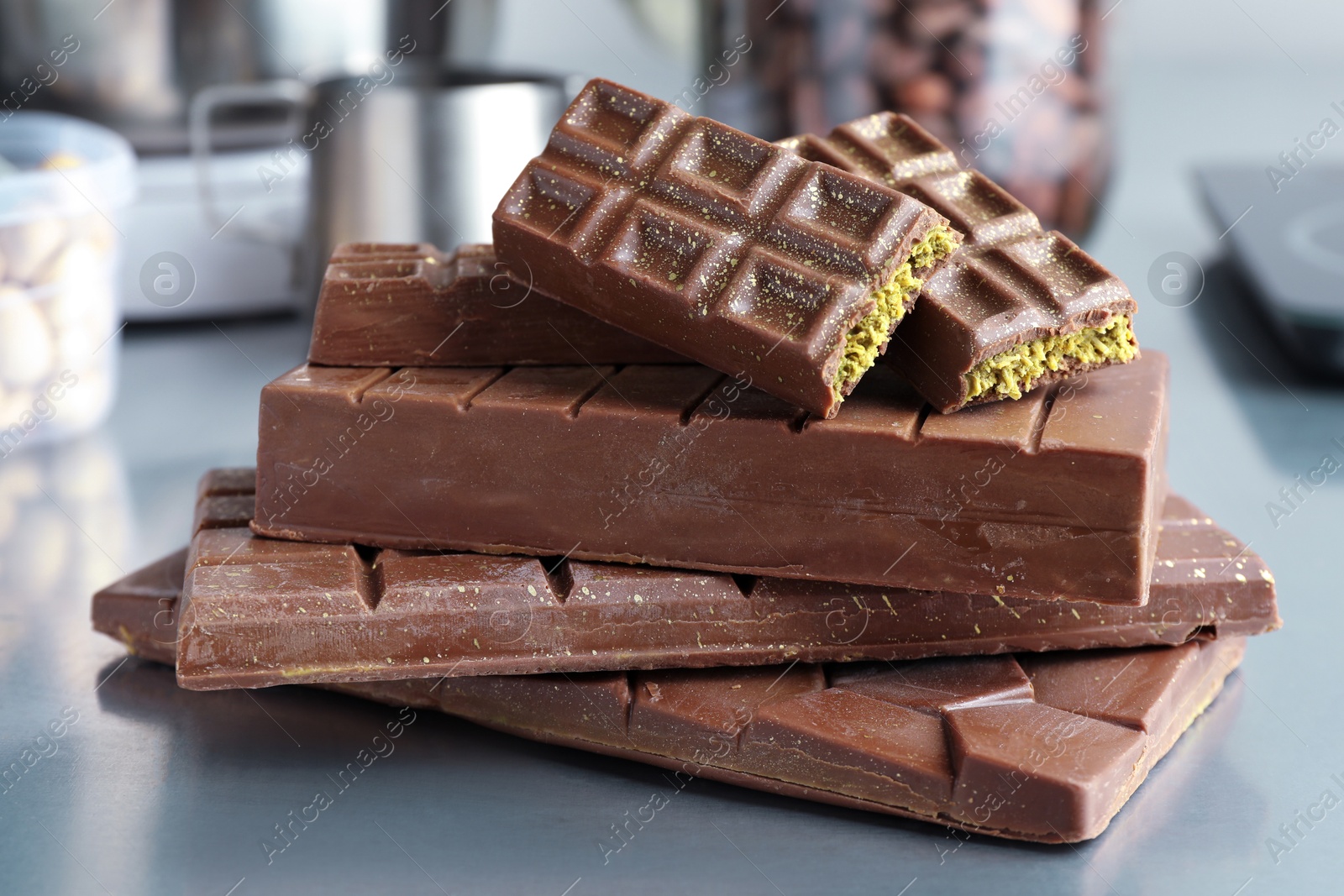 Photo of Stack of tasty Dubai chocolate bars with pistachios and knafeh on grey table, closeup