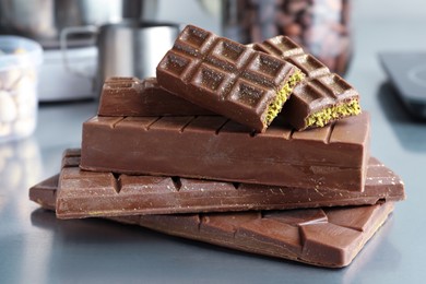 Stack of tasty Dubai chocolate bars with pistachios and knafeh on grey table, closeup