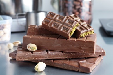 Stack of tasty Dubai chocolate bars with pistachios and knafeh on grey table, closeup