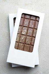 Photo of Tasty Dubai chocolate bars in packages with pistachios and knafeh on textured table, top view. Space for text