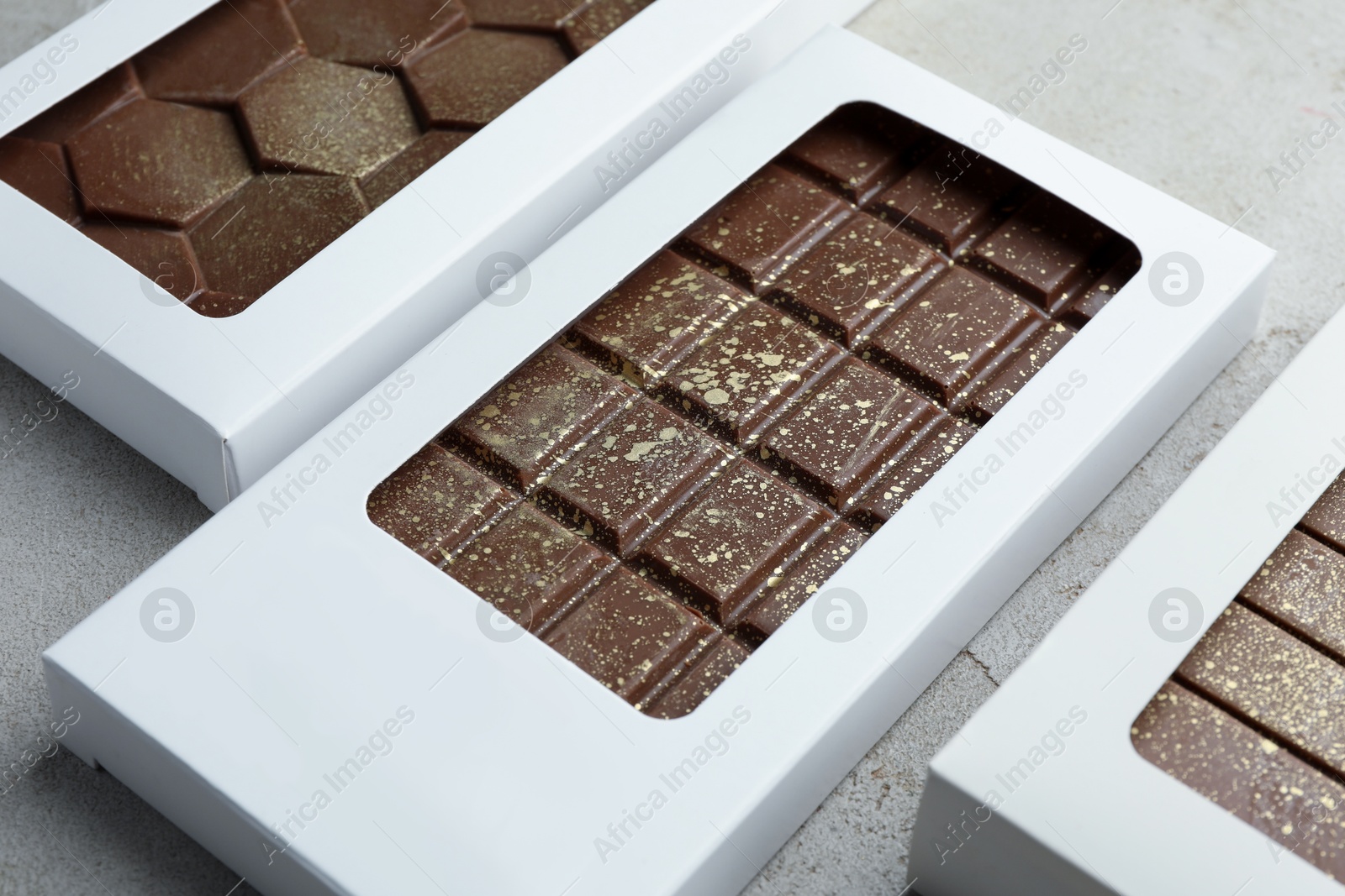 Photo of Tasty Dubai chocolate bars in packages with pistachios and knafeh on textured table, closeup. Space for text