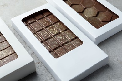 Photo of Tasty Dubai chocolate bars in packages with pistachios and knafeh on textured table, closeup. Space for text