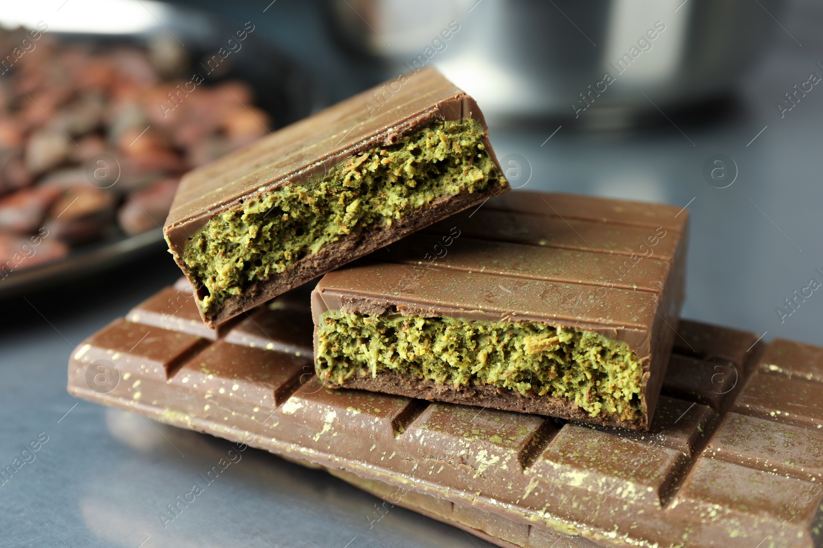 Photo of Tasty Dubai chocolate with pistachios and knafeh on grey table, closeup