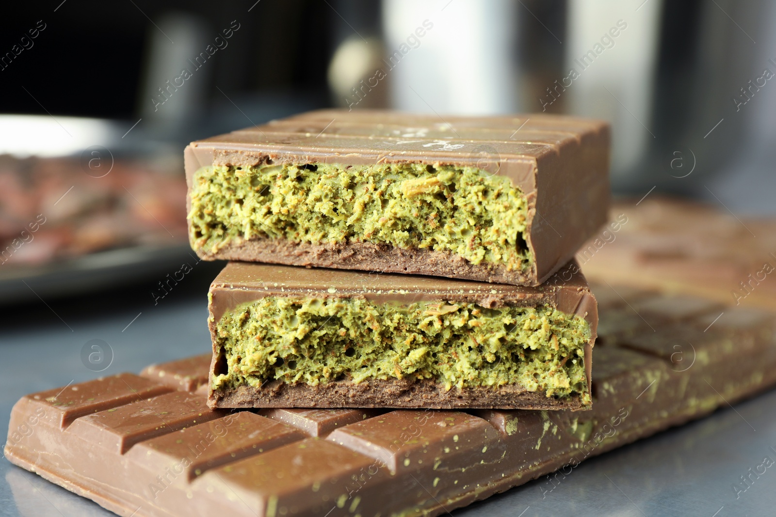 Photo of Tasty Dubai chocolate with pistachios and knafeh on grey table, closeup