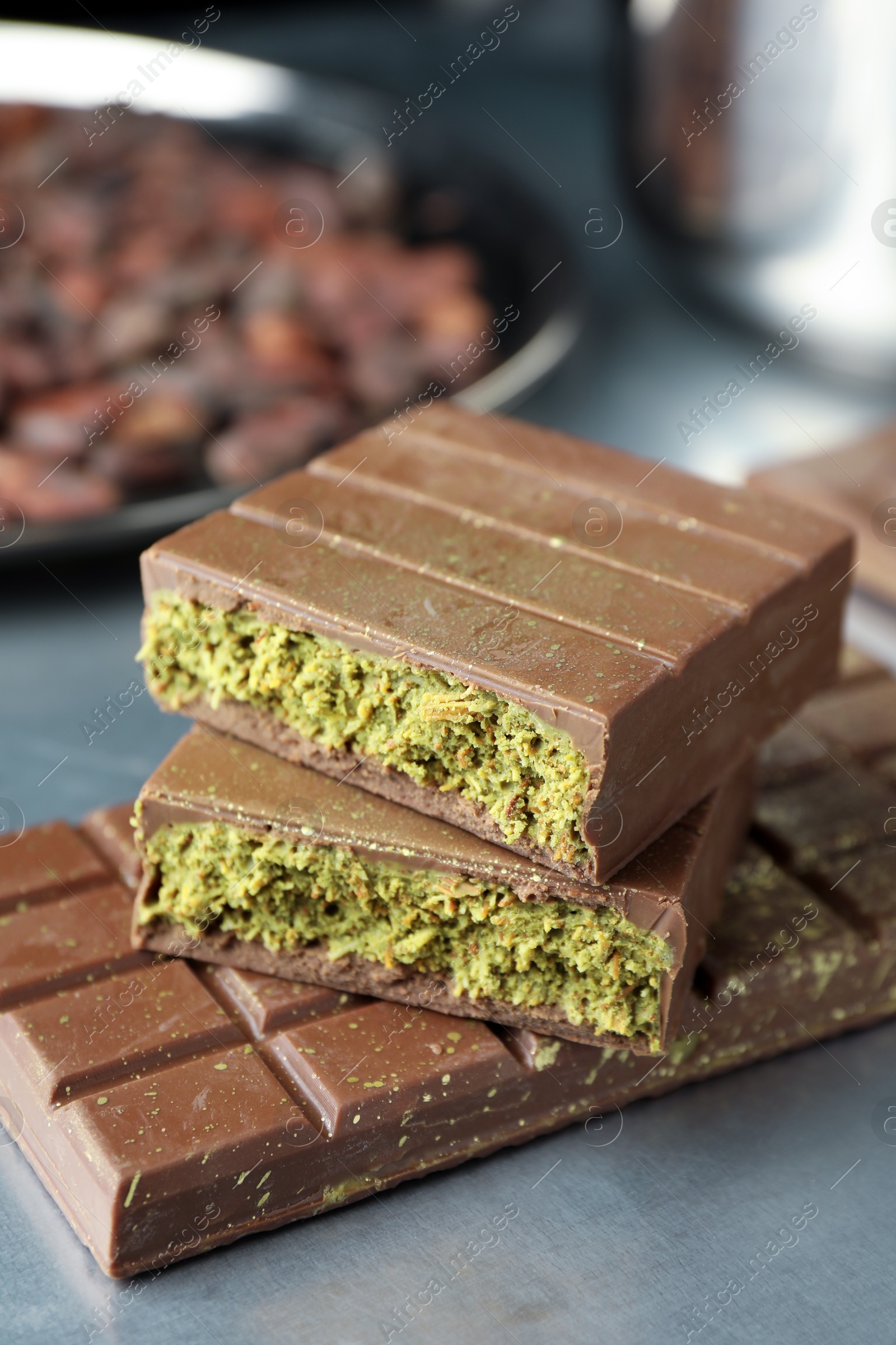 Photo of Tasty Dubai chocolate with pistachios and knafeh on grey table, closeup