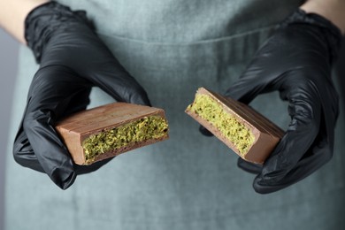 Woman holding pieces of tasty Dubai chocolate with pistachios and knafeh, closeup