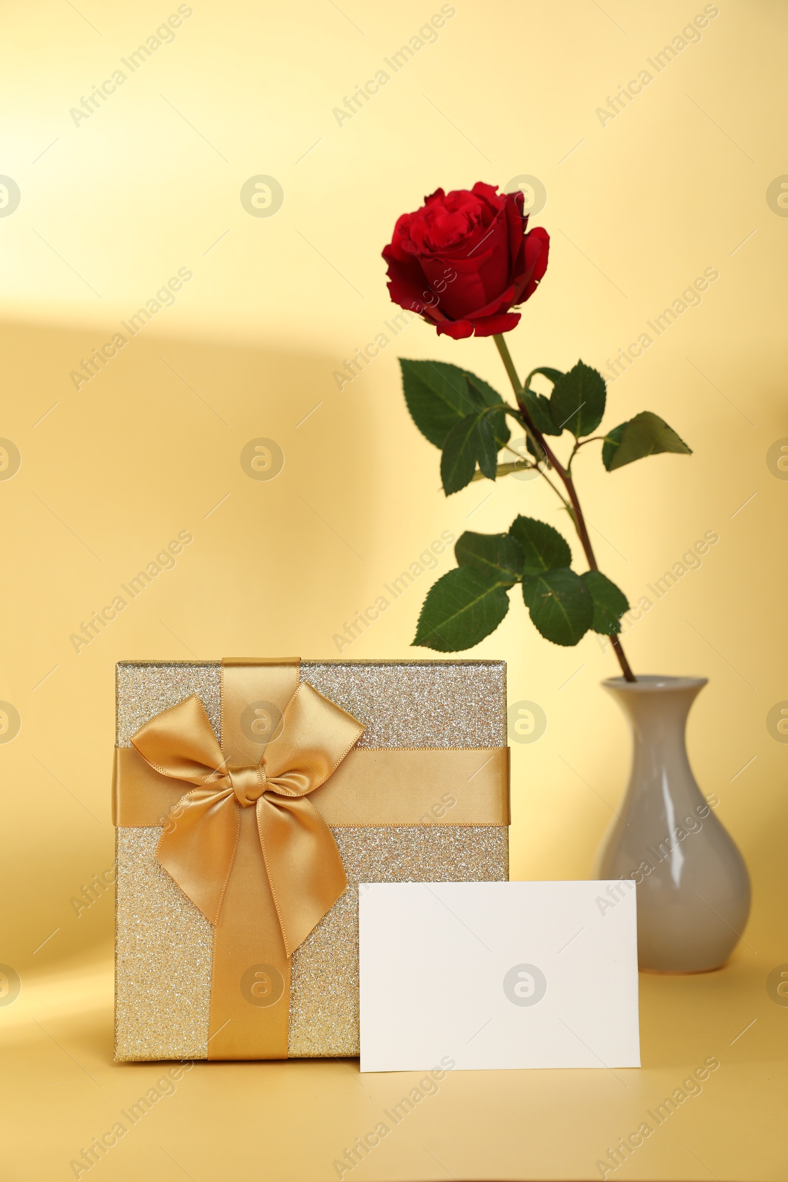 Photo of Romantic gift, rose and blank card on beige background. Space for text