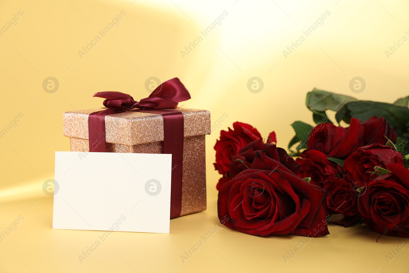 Photo of Romantic gift, roses and blank card on beige background. Space for text