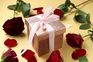 Romantic gift and roses on beige background, closeup