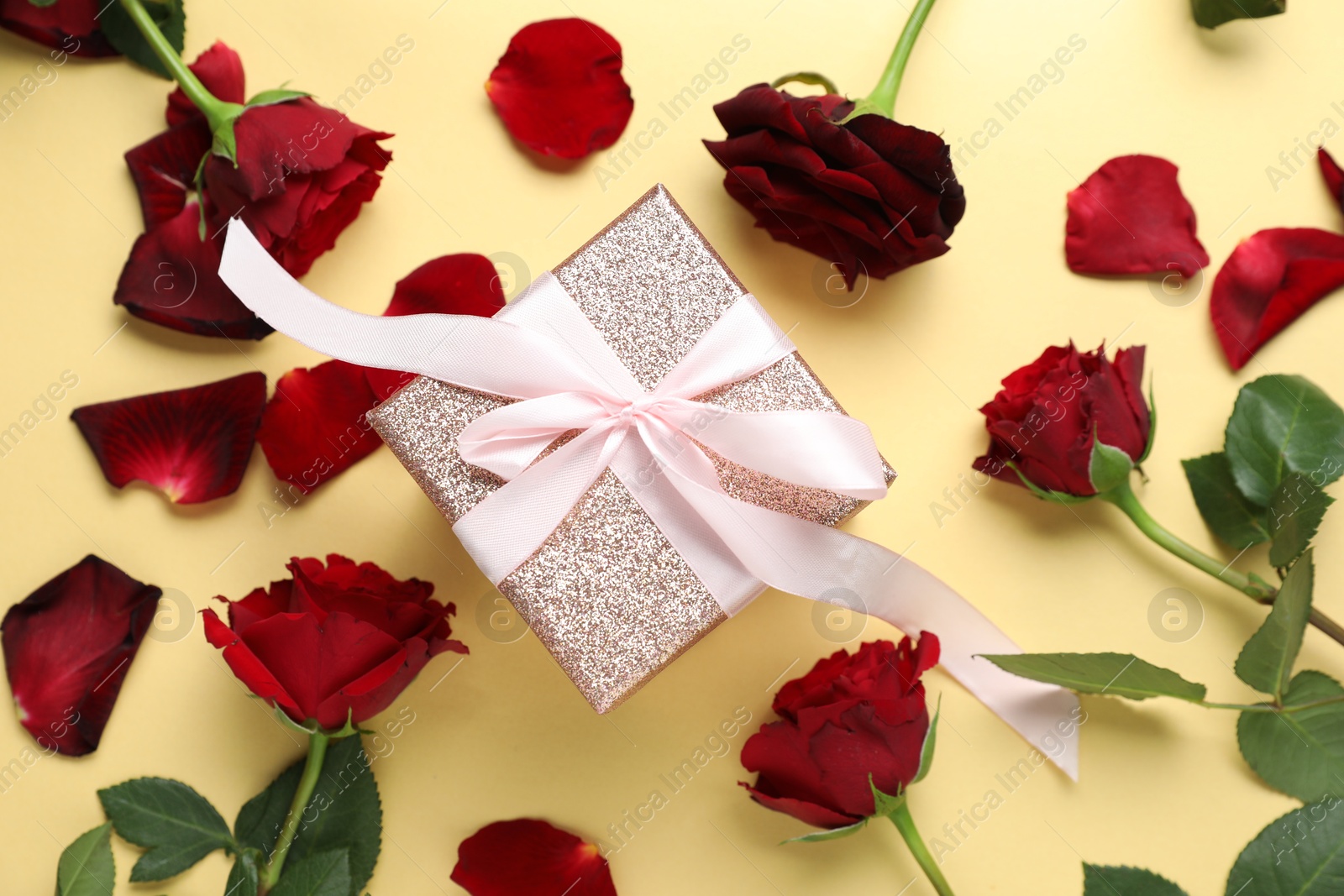 Photo of Romantic gift and roses on beige background, flat lay