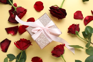 Romantic gift and roses on beige background, flat lay