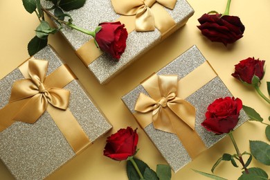 Photo of Romantic gifts and roses on beige background, flat lay