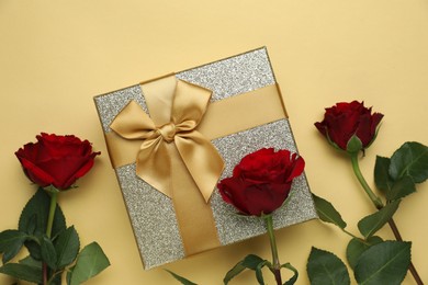 Romantic gift and roses on beige background, flat lay