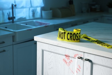 Photo of Yellow crime scene tape and bloody handprint on chest of drawers in kitchen. Forensic expertise