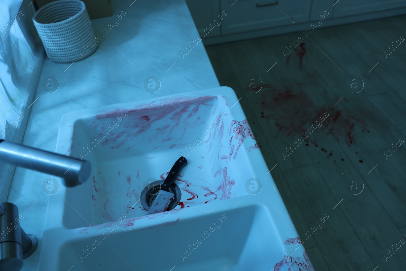 Photo of Knife, sink and floor smeared in blood indoors. Crime scene