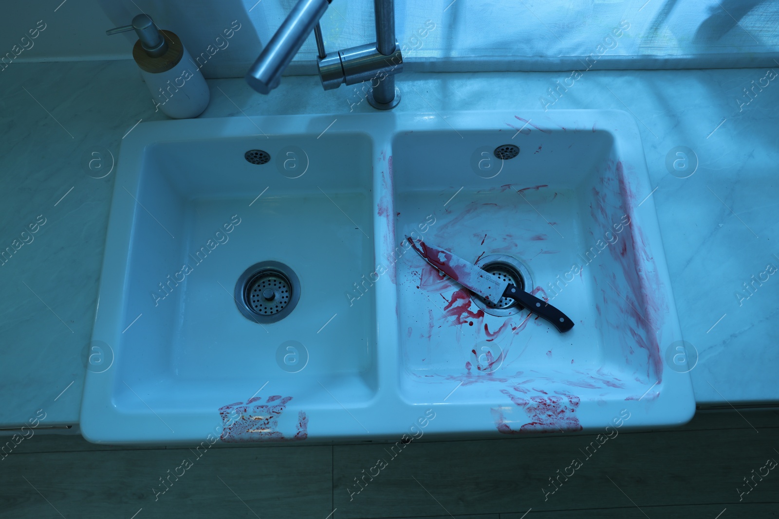 Photo of Knife and sink smeared in blood indoors, above view. Crime scene