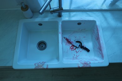 Photo of Knife and sink smeared in blood indoors, above view. Crime scene