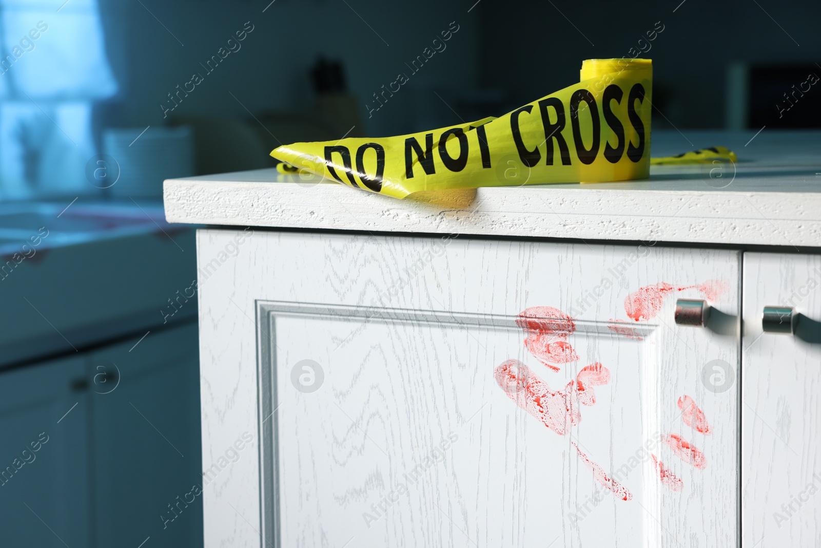 Photo of Yellow crime scene tape and bloody handprint on chest of drawers in kitchen. Forensic expertise