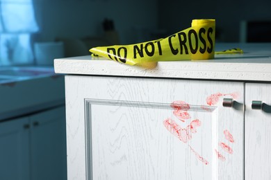 Photo of Yellow crime scene tape and bloody handprint on chest of drawers in kitchen. Forensic expertise