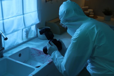 Photo of Forensic expert with camera working at crime scene indoors