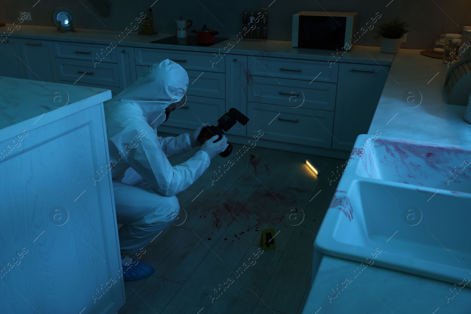 Photo of Forensic expert with camera working at crime scene indoors