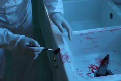 Photo of Forensic expert taking fingerprints from sink with brush at crime scene indoors, closeup