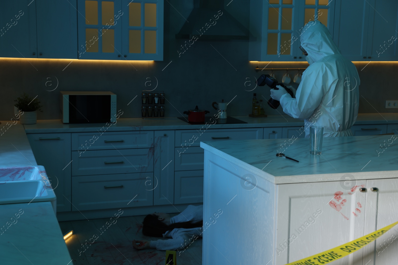 Photo of Forensic expert with camera working at crime scene in dark room