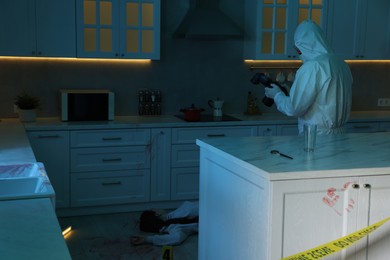 Photo of Forensic expert with camera working at crime scene in dark room