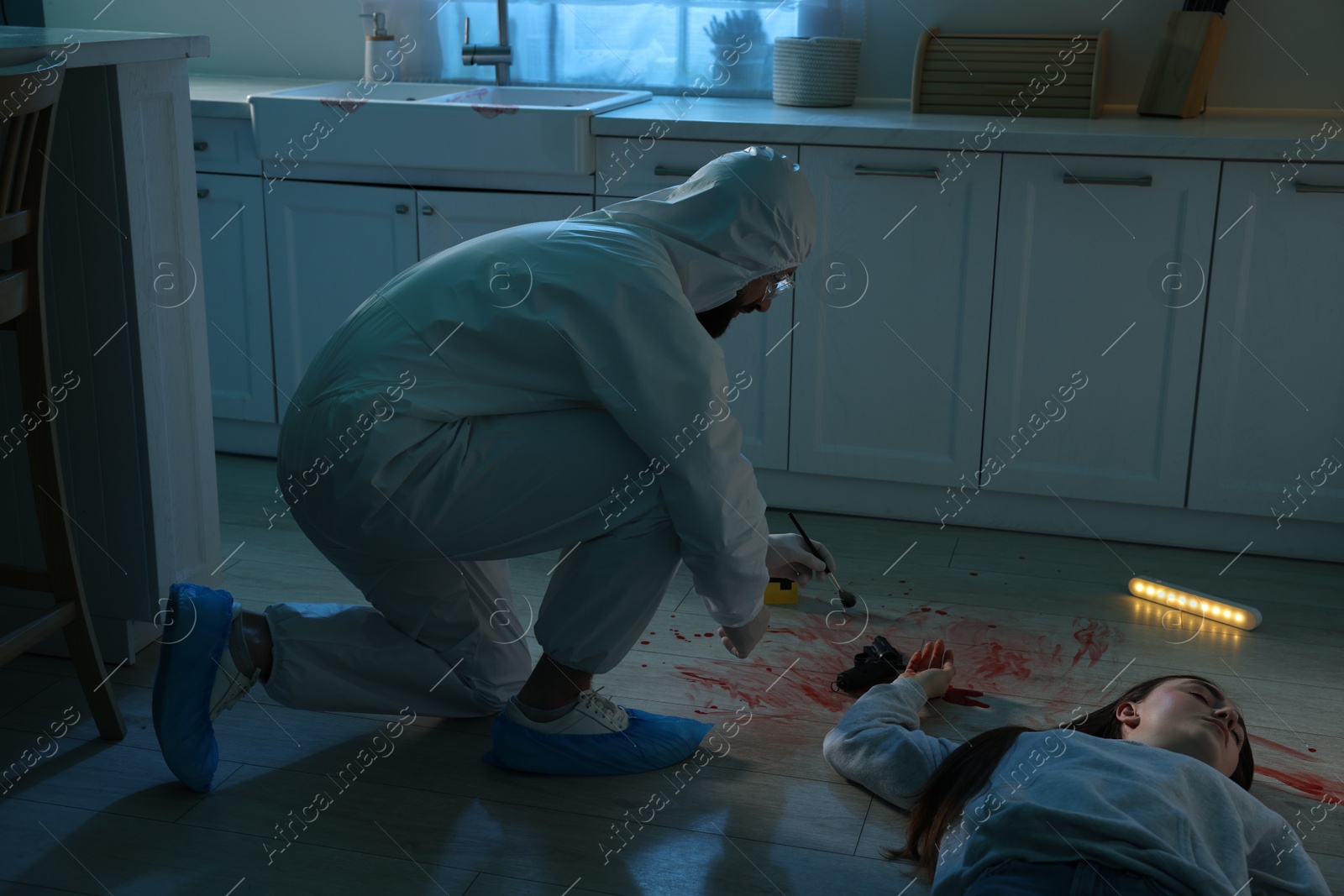 Photo of Forensic expert taking fingerprints with brush from gun and dead body at crime scene indoors