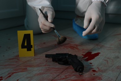 Photo of Forensic expert taking fingerprints with brush from gun, closeup