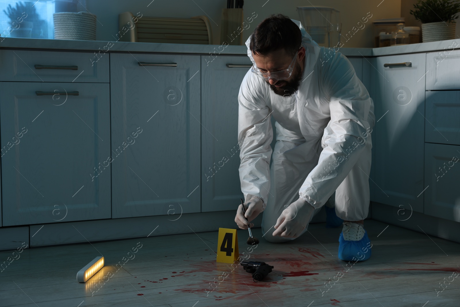 Photo of Forensic expert taking fingerprints with brush from gun at crime scene indoors