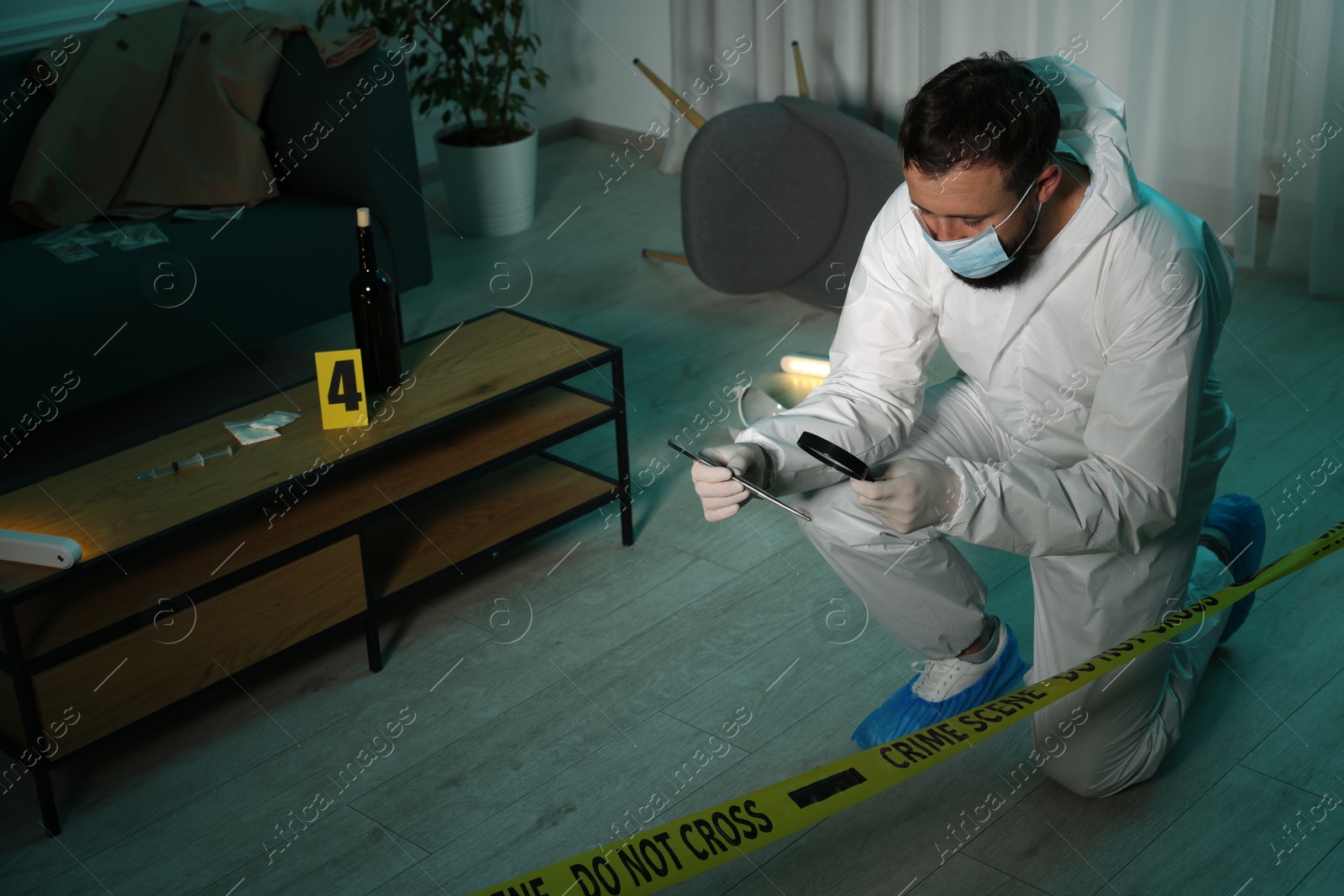 Photo of Forensic expert with tweezers examining hair through magnifying glass at crime scene indoors