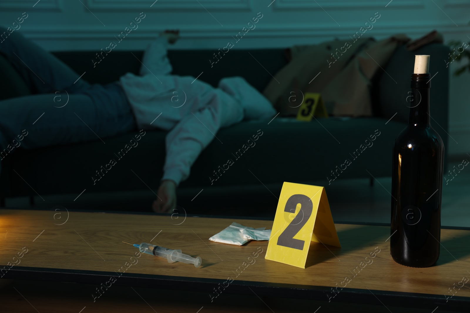 Photo of Dead woman's body on sofa indoors, focus on drugs, bottle of wine and numbered marker stand