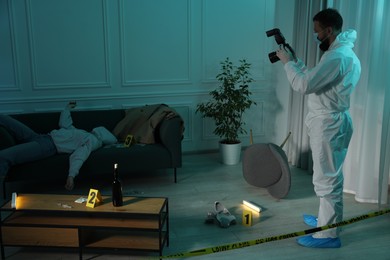 Forensic expert with camera working at crime scene and dead woman's body indoors