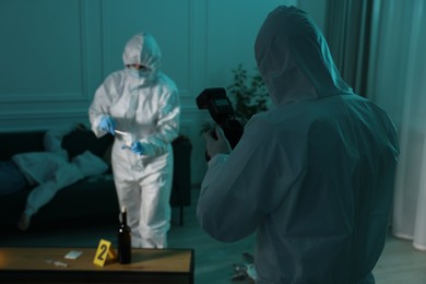 Photo of Forensic experts working at crime scene with dead woman's body indoors, selective focus