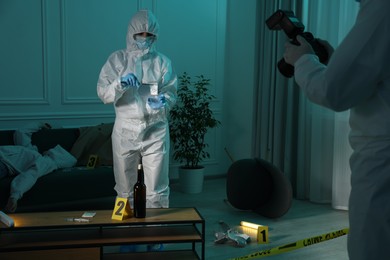 Photo of Forensic experts working at crime scene with dead woman's body indoors, closeup