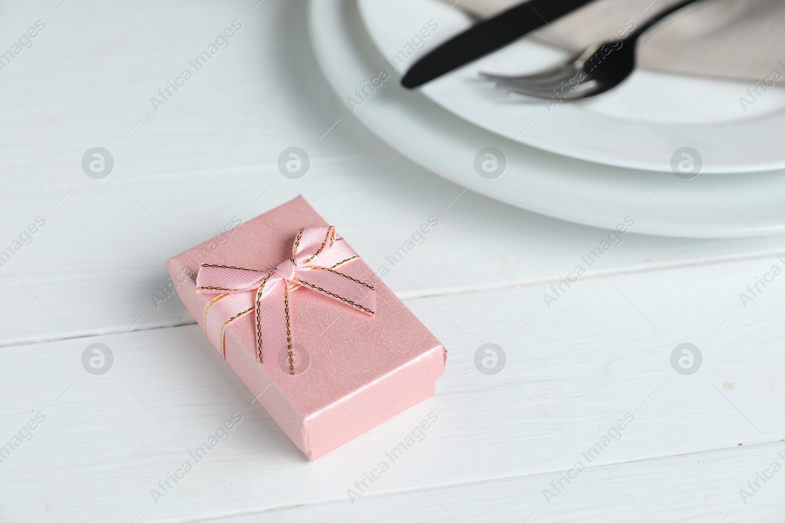 Photo of Beautiful table setting with romantic gift on white wooden background, closeup