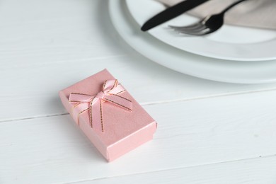 Beautiful table setting with romantic gift on white wooden background, closeup