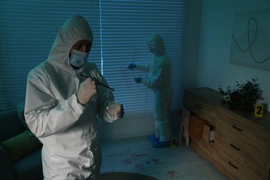 Photo of Forensic experts working at crime scene indoors