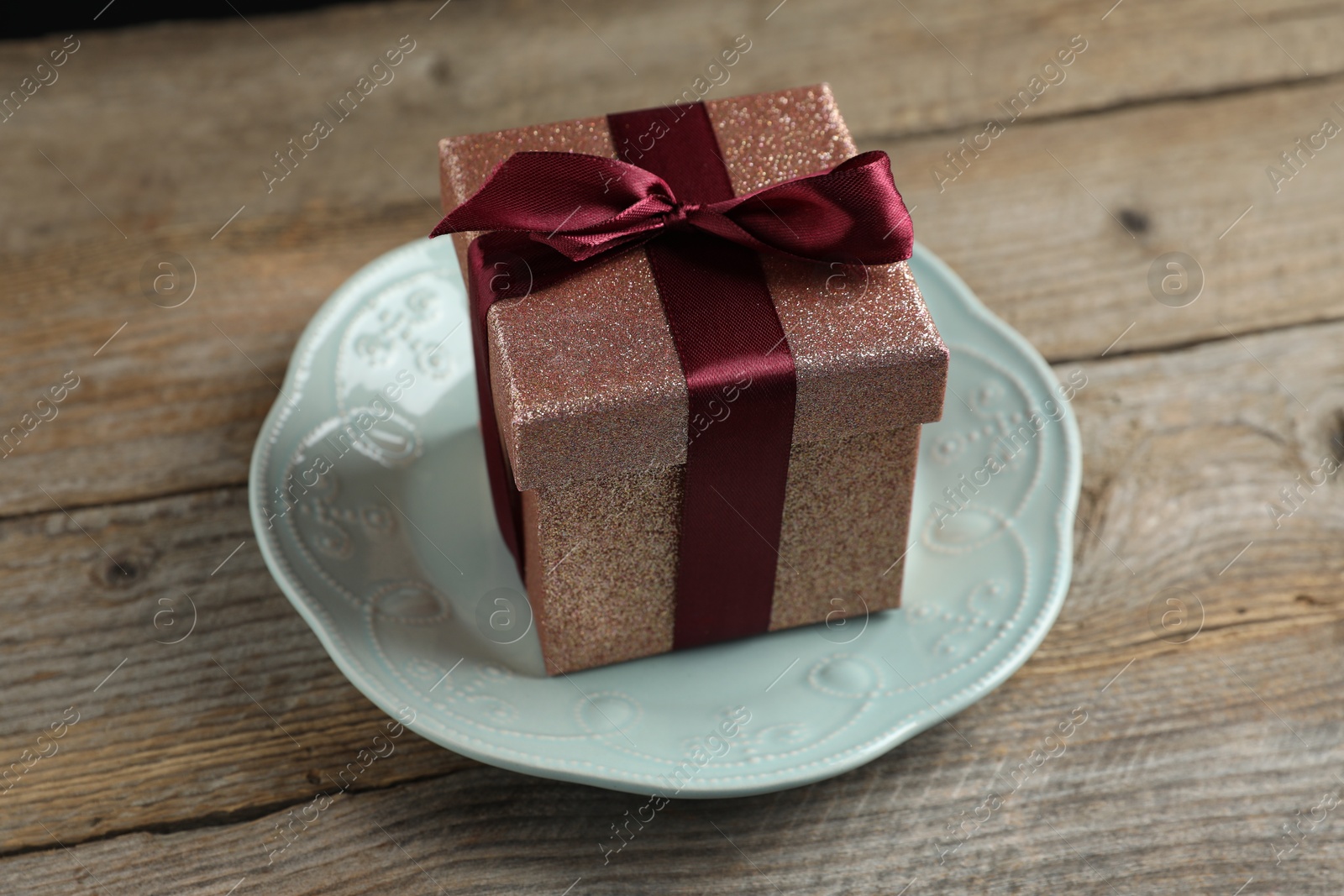 Photo of Romantic gift and plate on wooden table, closeup