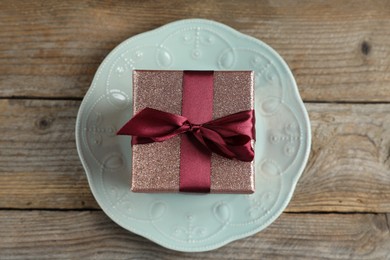 Romantic gift and plate on wooden table, top view