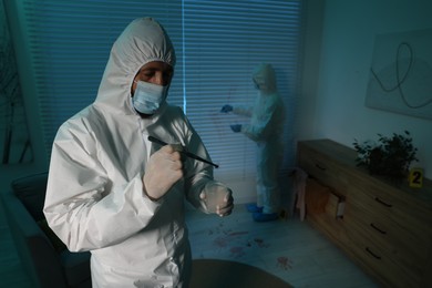 Photo of Forensic experts working at crime scene indoors